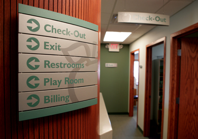 interior picture of Saks Wellness Center in Gaylord, Michigan - wayfinding directional sign echoes the clinic's color scheme of calming taupe and green with rich wood trim and accents