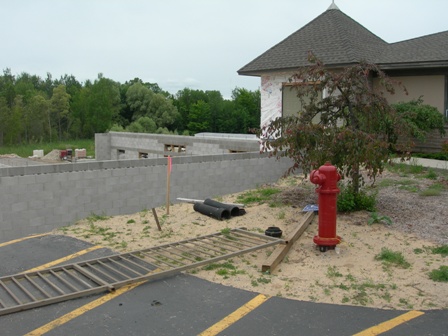 photo of construction progress for Addition to Word of Life Baptist Church in Alpena - concrete masonry unit wall is now visible above ground level from the front parking lot