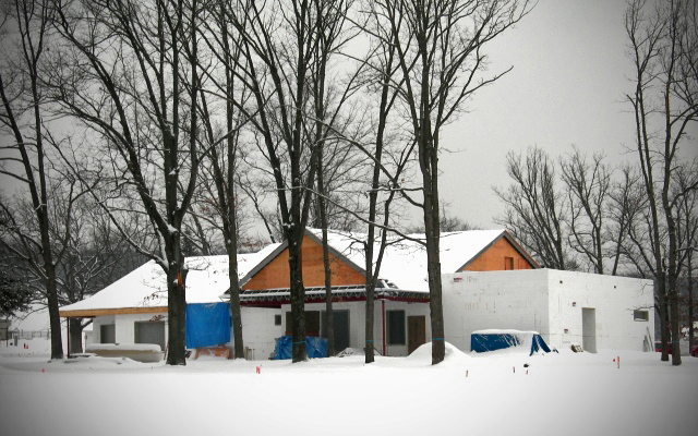 picture of dining hall with exterior walls erected, roof structure is on and covered with snow