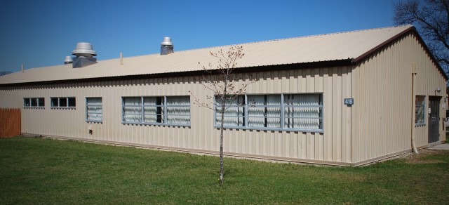 exterior picture of the CRTC Multi-Purpose Building 416 before improvements were made - the building has light tan metal siding and roof, gray window trim