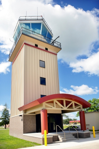 picture of Air Traffic Control Tower at Alpena Combat Readiness Training Center - Entrance Canopy - curved red metal canopy supported by red columns, control tower building is light tan with red accents