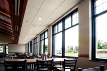 interior picture of Dining Hall at Alpena Combat Readiness Training Center - view of tables along one of the window walls which let in plenty of natural light supplemented by overhead recessed light fixtures