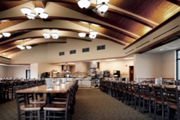 interior photo of Base Dining Facility at Alpena Combat Readiness Training Center - the curvature in the roof beams add architectural interest and frame the pendant light fixtures