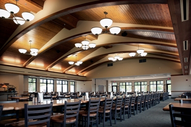 Alpena Combat Readiness Training Center Dining Hall accommodates 350 personnel - wood plank ceiling with curved beams framing pendant light fixtures supplemented by plenty of natural light through the building's many windows.