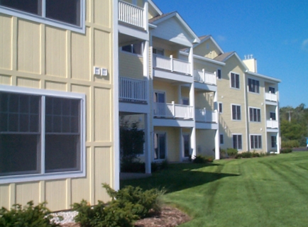 photo of Multi-Family Residential Development - Harborage Pointe Waterfront Condominiums in East Jordan, Michigan - lakeside elevation with yellow siding, white trim at windows and balconies