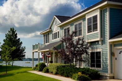 picture of Harborage Bay Condominium with blue siding and white trim - this was just a bit of luck - see the sailboat in the bay?  That just so happens to be one of our employees!  What a coincidence!