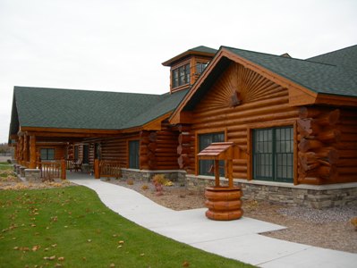 exterior photo of Freighter View Assisted Living Facility in Sault Ste. Marie, Michigan - covered porch for an outdoor gathering space - log and timber construction with green shingled roof and lower wall of mixed stone siding
