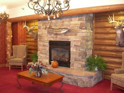 interior photo of Freighter View Assisted Living Facility in Sault Ste. Marie, Michigan - welcome center stone hearth fireplace and trophy mounts against natural log wall with timber framing