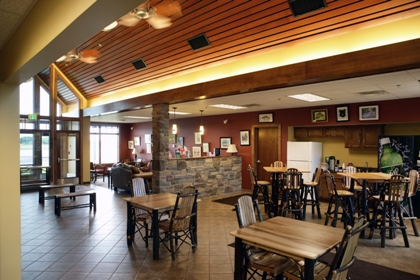 interior picture of the Lobby/Passenger Waiting area at Gaylord Regional Airport General Aviation Terminal - vaulted wood plank ceiling, stone half wall at lounge and quarry tile floor