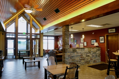 picture of Entrance Lobby and Passenger Waiting Area at Gaylord Regional Airport General Aviation Terminal - vaulted wood plank ceiling, ceiling fans with propeller style blades, stone half wall separates concession area from lounge
