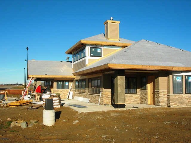 workmen with ladders working on siding and roof