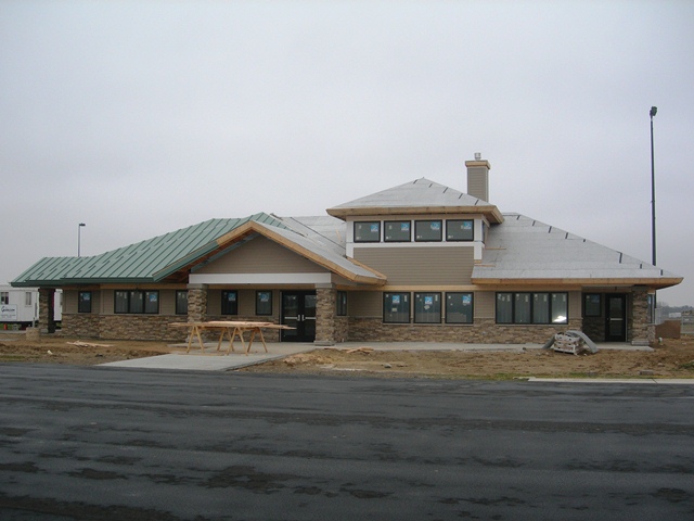 building under construction with tan siding, green metal roof and trim