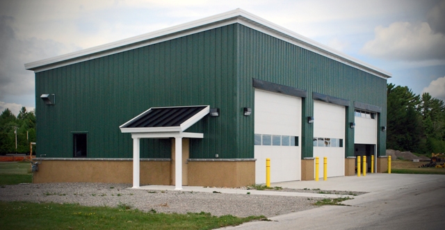 snow removal equipment building with green metal siding, white overhead doors and white trim