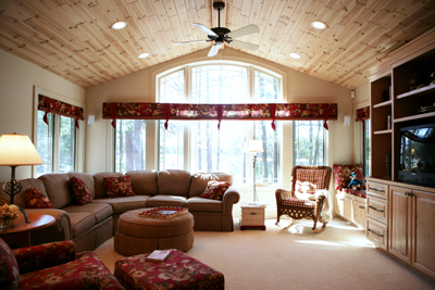 picture of lakefront home on Manuka Lake - this interior photo of the home's family room shows vaulted wood plank ceiling with recessed lighting - the sunlight coming through the window lights and warms the soft wood accents in the space