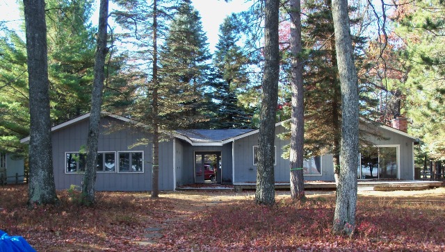 picture of single level home on Lake Margrethe, Grayling before any work begins - grey wood siding with white trim