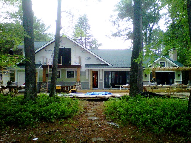 Lake Margrethe custom home lakeside exterior, green and grey siding, white trim and fieldstone accents