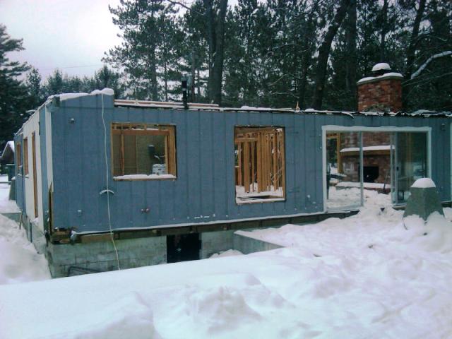 the snow is pretty deep but work continues - the fireplace and interior framing are visible through the window and door openings