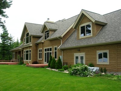 picture of lakeside custom home on Otsego Lake - this exterior photo was taken of the lakeside elevation - wood siding, architectural shingles, custom windows and french doors for multiple outdoor decks