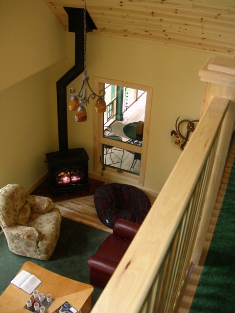 interior photo taken from upper level, looking down toward wood stove in the great room