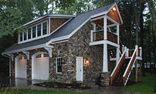 Photo of custom garage built for lakefront home in Lewiston, Michigan.  The fieldstone exterior, cedar shakes and deck, with white columns, trim and white windows and doors matches the color palette of the home.