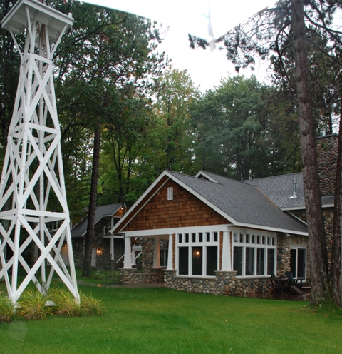 exterior photo of fieldstone home with cedar shake siding, white window and soffit trim, and grey architectural shingle roof