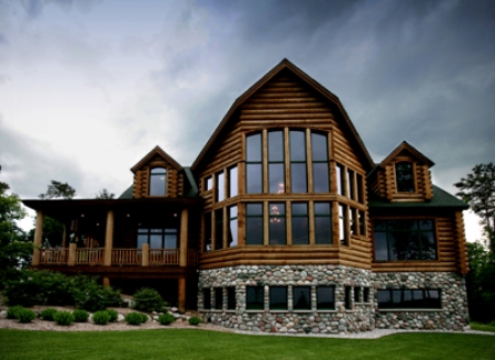 exterior photo of custom log home in Gaylord - log siding, field stone lower level and timber framed porch