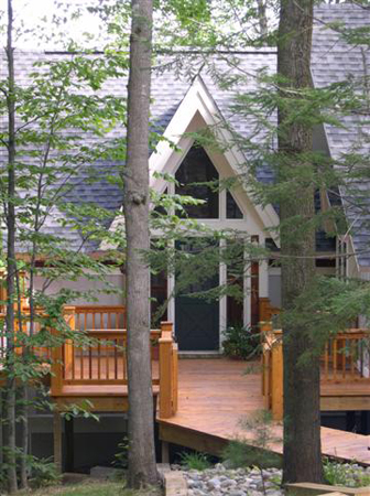 picture of main entry of waterfront home on Kassuba Lake - natural wood porch/deck and walkway weaves through trees and beds of river rock