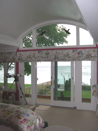 this interior photo is looking out from the master suite toward the lake - french doors open onto deck/balcony with glass safety railing which allows an unobstructed view of the lake - ceiling curvature is repeated in the window design, which lets in natural lighting for the space