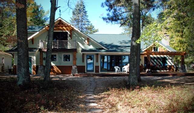 An exterior photo of lakefront home in Lewiston, Michigan, before renovations began.  The home is a total fieldstone exterior with small windows.