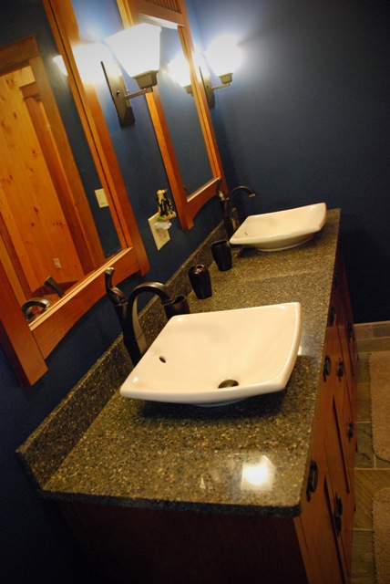 interior photo of master bathroom double vanity sink with top-mounted basins, dark blue walls and wood accents