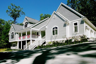 picture of custom home at Mountain Lake Golf Club - this exterior photo is of the home's front elevation showing grey siding and architectural shingles with white trim and railing for upper and lower covered porches and stairways