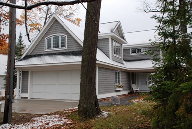 picture of lakeside home in Topinabee, Michigan - this exterior photo facing the attached garage is taken from the road-side elevation, on an angle which shows the dormer of the bonus room over the garage and walkway to the home's main entrance