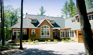 picture of custom home on O'Rourke Lake in Gaylord, Michigan - this exterior photo shows natural cedar siding with white trim, architectural shingled roof and custom windows throughout