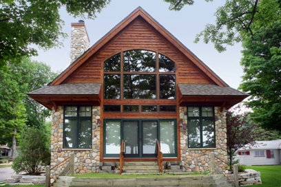 picture of custom lakeside home on Otsego Lake - this exterior photo was taken of the lakeside elevation steps leading up to sliding glass entrance doors - fieldstone on lower level, with cedar siding on upper level, architectural roof shingles and custom windows throughout