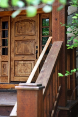 picture of custom lakeside home on Otsego Lake - this exterior photo was taken of the main entrance on the roadside elevation of the home while standing at the foot of the stair leading up to the covered porch over the custom wood entry door and sidelights