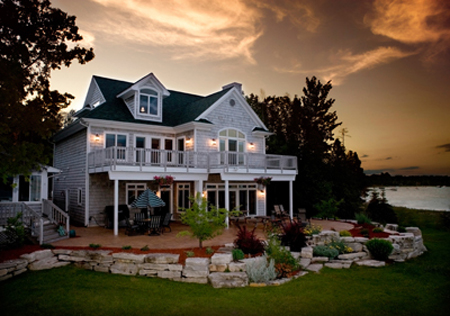 picture of Oyster Bay Residence on Lake Charlevoix MI (picture of original 2000 home taken at dusk with the lake in the background)